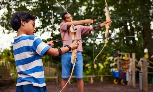 Un père et son fils pratiquent le tir à l'arc.